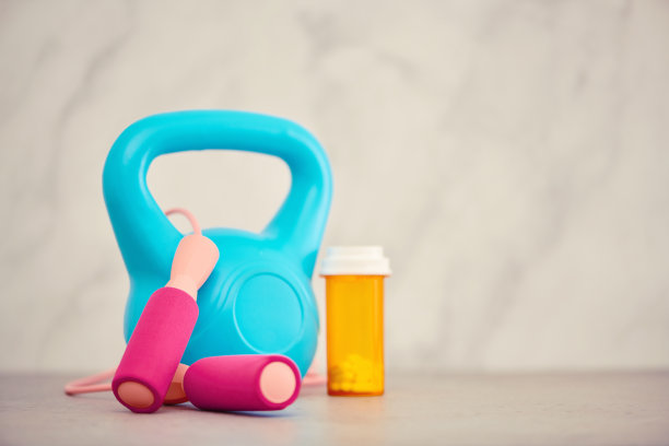壶铃和跳绳在明亮的环境下，旁边是一瓶药丸，以显示药物和健身的对比。空间复制图片下载