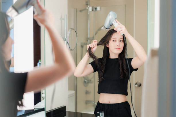 用吹风机吹干头发的年轻女子图片下载