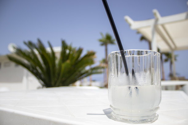 冰泉水。夏日鸡尾酒或柠檬水，以棕榈树为背景，在海边的咖啡馆里。海滩餐厅吧台上的水或鸡尾酒。图片下载