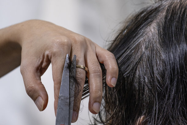 新正常的女孩左手拿着灰色的头发用剪刀剪掉金色的女人的头发图片下载