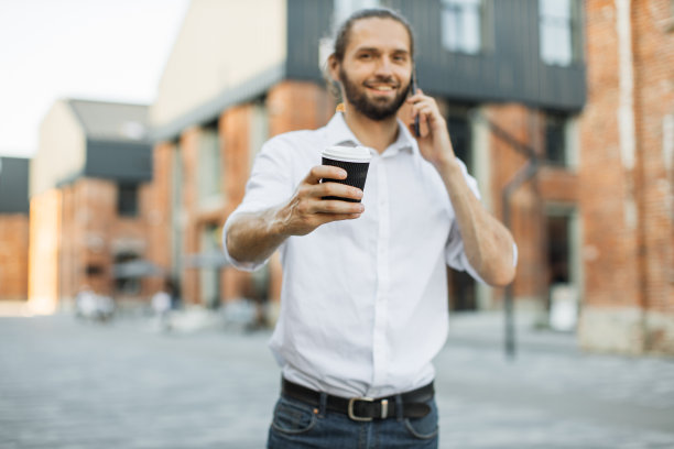 英俊的商人拿着外卖杯，打电话。图片下载