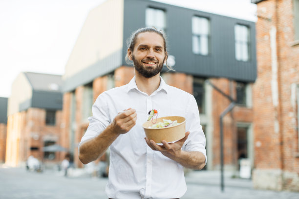 英俊的商人在工作间隙吃健康的沙拉。图片下载