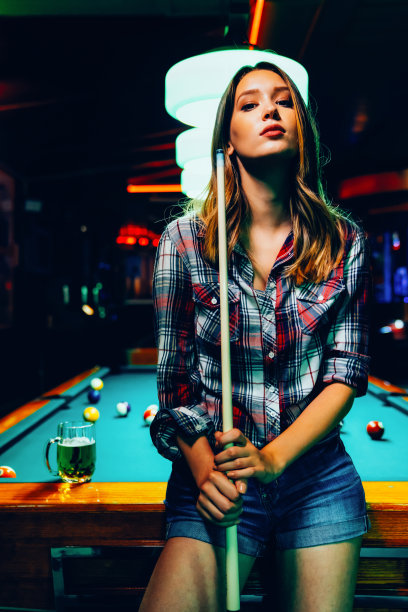 年轻漂亮的女孩在打台球。愉快的消遣、休息、娱乐。图片下载