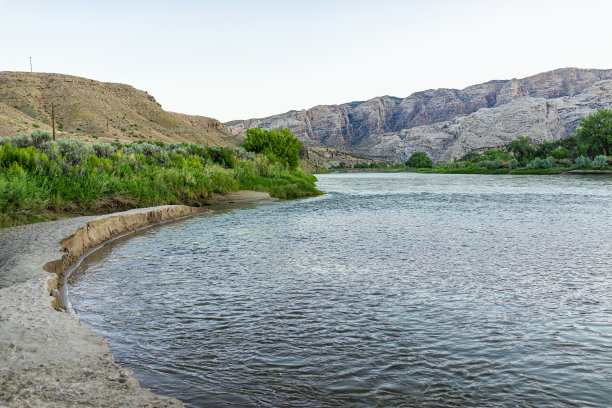 绿河野营地水在恐龙国家纪念碑公园在黑暗的日出早晨与绿色的植物和峡谷岩石悬崖景观与无人图片下载
