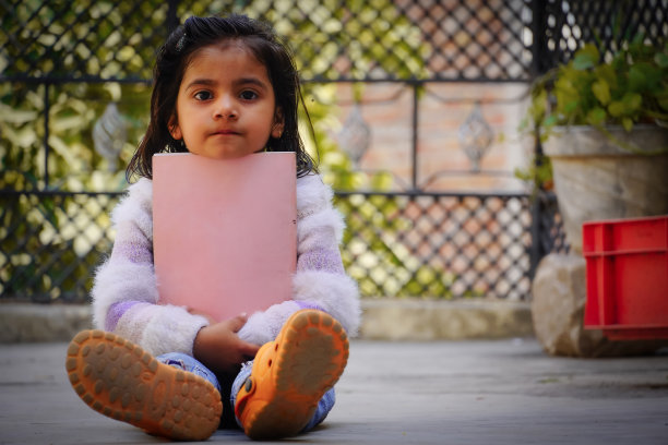 欢快的小女孩拿着粉红色的书图片下载