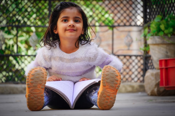 可爱的小女孩读着这本书，脸上带着漂亮的微笑和表情图片下载