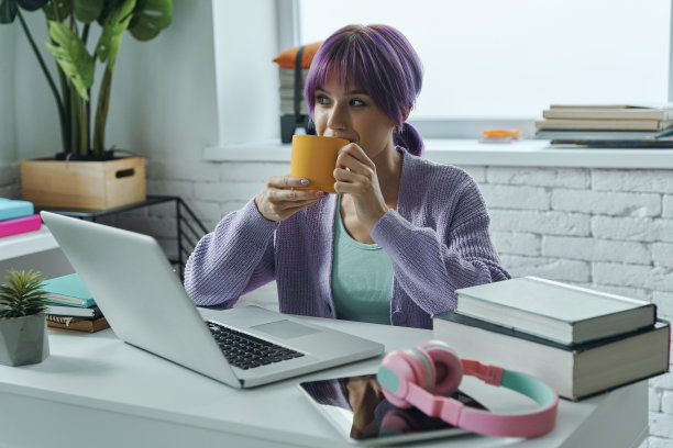 有思想的年轻女子和紫色的头发享受热饮图片下载