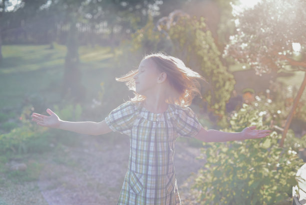 一个穿着裙子的女孩在一个阳光明媚的日子走在街上。图片下载