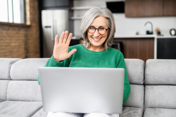 美丽的高级妇女使用笔记本电脑在家里进行视频通话图片下载