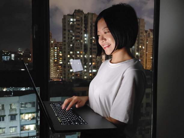 亚洲女性晚上在家用笔记本电脑工作图片下载