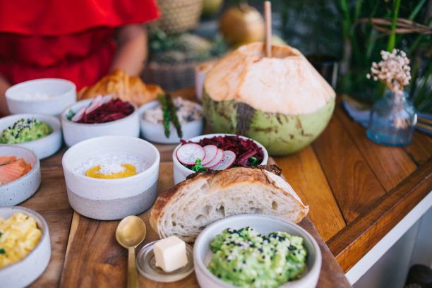照片中女性坐在自助餐厅的餐桌旁，午餐点了健康的食物，绿色鳄梨色拉和面包，美味的奇亚酸奶和甜菜根沙拉作为餐厅的开胃早餐图片下载