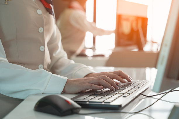 在机场值机柜台工作的空姐。员工使用台式电脑工作。图片下载