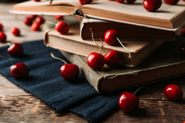 成熟的红色甜樱桃和书籍在质朴的木制背景的大气照片。有选择性的重点。浅景深。图片下载
