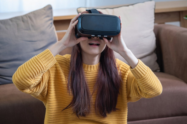一位快乐的亚洲女性度假时在家里玩VR 3D虚拟现实游戏。图片下载