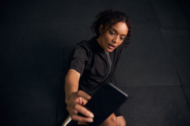 非洲裔美国女性在用手机自拍。美丽的混血女性在健身房用手机自拍。高质量的照片图片下载