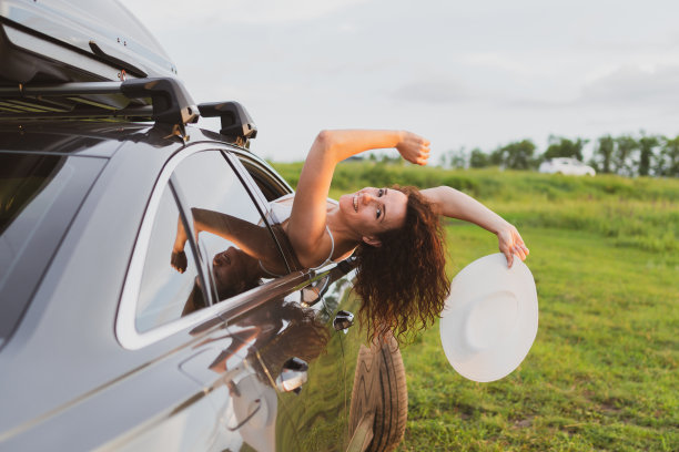 美丽的年轻女子开车旅行，探出窗外，玩得很开心图片下载