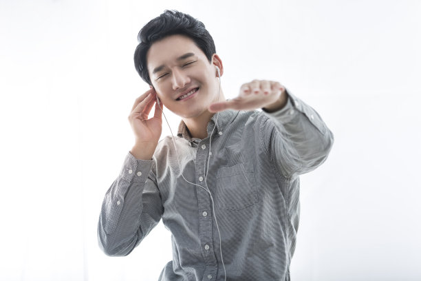 戴着耳机听着音乐，兴奋地跳着舞，充满活力和帅气的中国日韩青年——照片图片下载