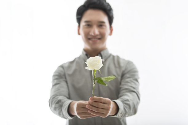 赠送的白色玫瑰花束，双手捧着充满活力和帅气的中国日韩青年男子——stock photo图片下载