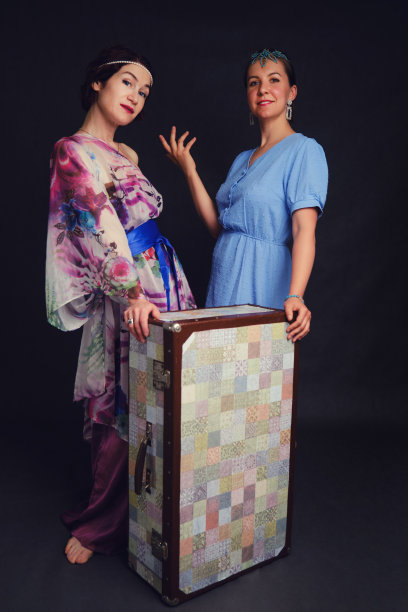 一个快乐的女人穿着亚洲服装，在工作室的黑色背景上提着一个手提箱。黑色背景上背着包的微笑女人图片下载