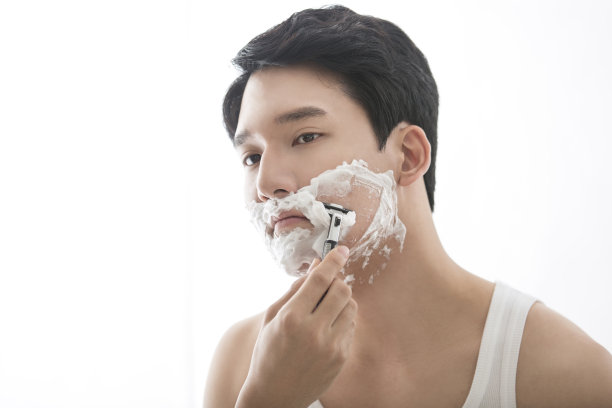 年轻的中国男子展示剃须产品，剃须润滑产品，剃须后抗过敏产品-库存照片图片下载
