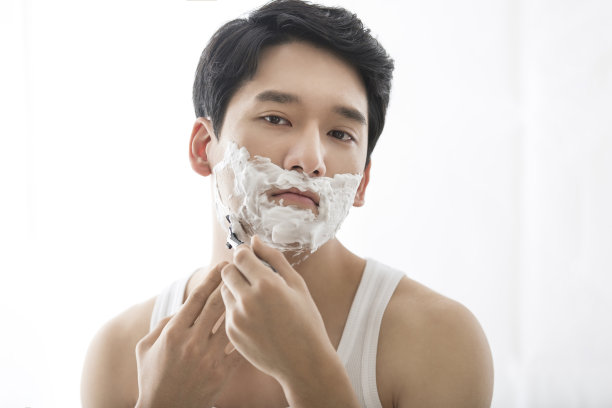 年轻的中国男子展示剃须产品，剃须润滑产品，剃须后抗过敏产品-库存照片图片下载