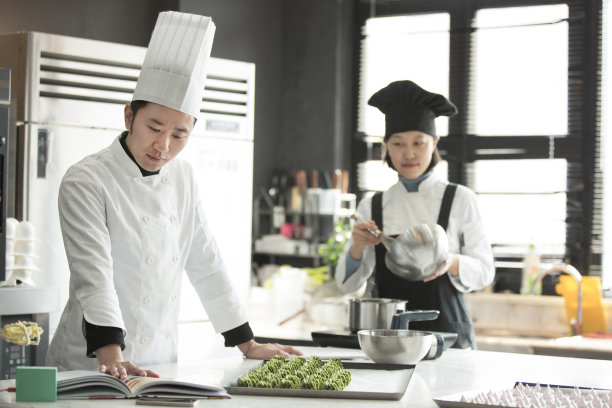 年轻的中式糕点师在读一本营养学书-库存照片图片下载