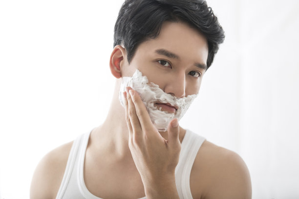 年轻的东亚男子剃须前的镜像库存的照片图片下载