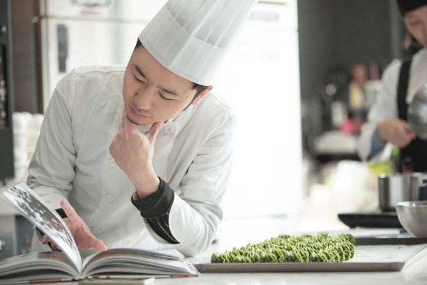 年轻的中式糕点师在读一本营养学书-库存照片图片下载