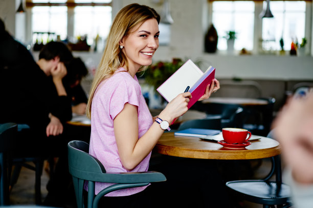 微笑着心满意足的女青年在食堂拿着笔记本图片下载