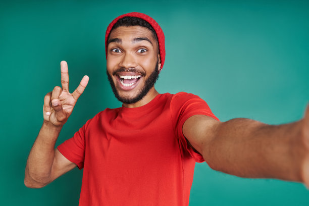 一名兴奋的非洲男子在绿色背景下自拍图片下载