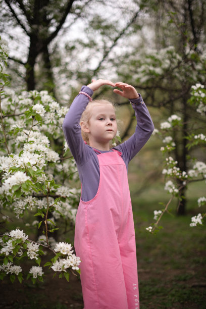 小女孩在花园里的花树旁跳舞。图片下载