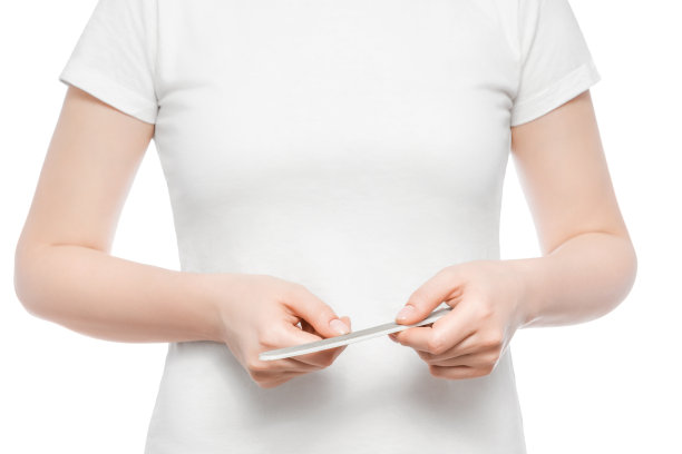 一个穿着白色t恤的女人修剪指甲的镜头。近,孤立。图片下载