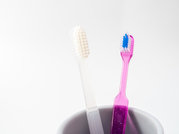 牙刷放在白色背景的杯子里图片下载