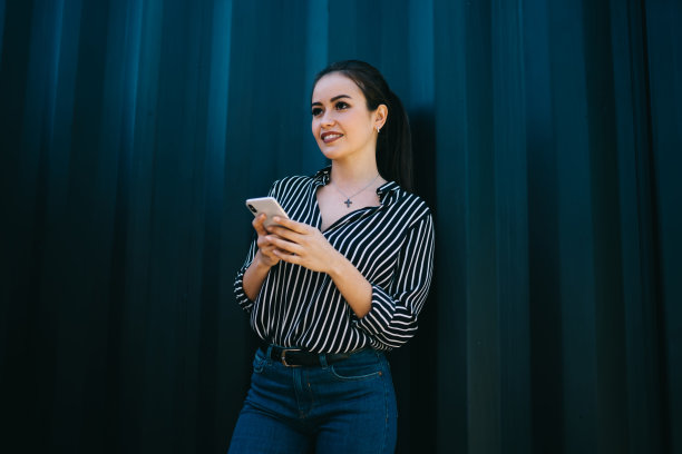 在智能手机网络的宣传区，无忧无虑的时髦女孩在闲暇时若有所思地看向别处，年轻的千禧一代与现代蜂窝技术的思维接近促销背景图片下载