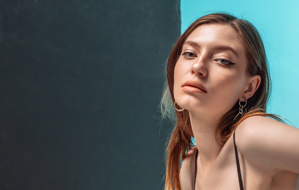 皮肤漂亮的女人。女性模特摆蓝色背景与文字空间图片下载
