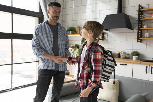 英俊的年轻强壮的父亲和他十几岁的儿子一起度过优质的时间，有乐趣，享受在一起。回归学校理念图片下载