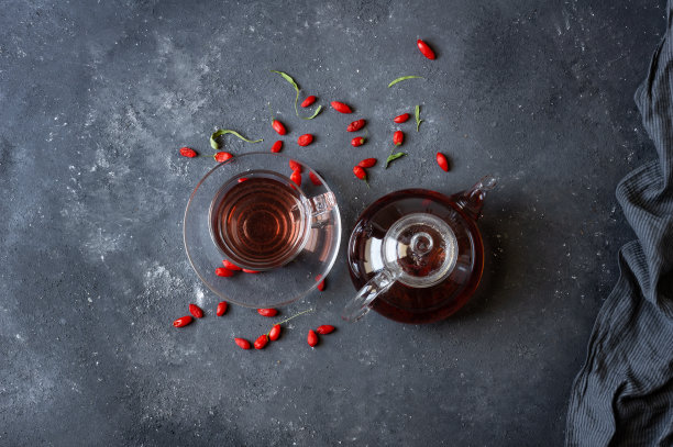 一杯草本枸杞茶，新鲜的枸杞放在质朴的桌子上图片下载