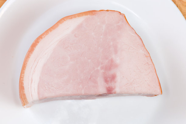 盘子上一块煮过的烟熏火腿的俯视图图片下载