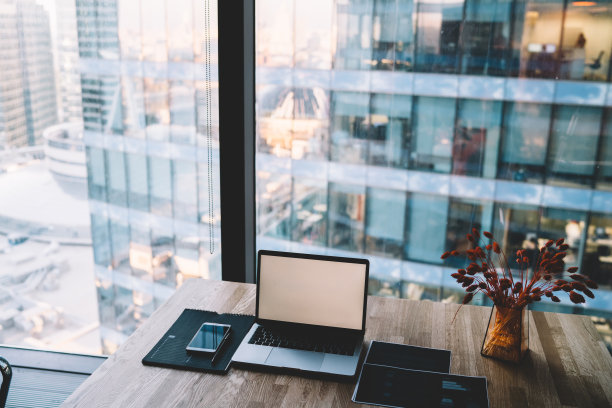 现代职场，笔记本电脑和智能手机放在靠近窗户的桌子上图片下载