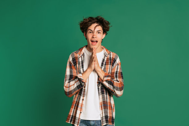 富有表现力的年轻男孩的肖像，青少年在休闲风格的衣服摆出孤立的绿色工作室背景。回归校园，情感，青春，时尚理念图片下载