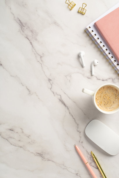 经营理念。俯视图垂直的工作站的照片粉红色的组织者钢笔金色的活页夹电脑鼠标无线耳机和杯热的饮料在白色大理石的背景图片下载