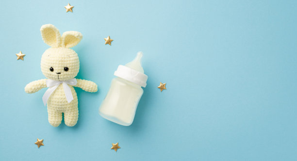 小配件的概念。顶视图的针织兔玩具奶瓶和金色的星星在孤立粉彩蓝色的背景与copyspace图片下载