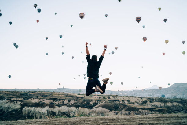 在岩石地带用气球跳跃的人图片下载
