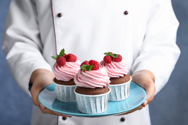 糕点厨师拿着盘子与甜纸杯蛋糕的蓝色背景，特写图片下载