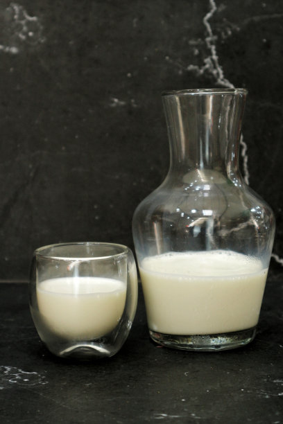玻璃容器鲜牛奶。黑色背景。图片下载