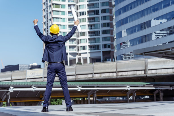 施工工程师身着安全服，团队手持白色黄色安全帽，安全设备在施工现场。土建工程师安全帽保护头。工程概念图片下载