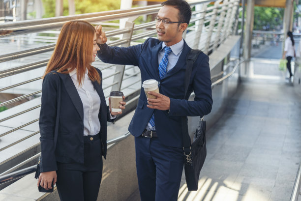 商人在办公室外的现代城市里喝咖啡。手牵手带走咖啡杯一起聊天开心好玩。商务人士正装配一杯咖啡图片下载