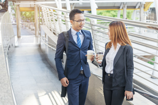 商人在办公室外的现代城市里喝咖啡。手牵手带走咖啡杯一起聊天开心好玩。商务人士正装配一杯咖啡图片下载