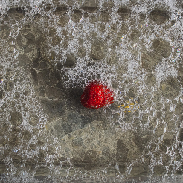 石头背景上覆盖着泡沫水球的红色草莓。平的概念。图片下载