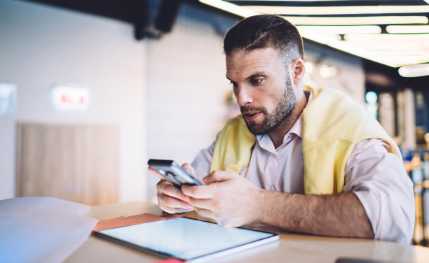 聪明的休闲男性博主享受移动网络的时间，用触控板在社交网页上策划内容发布，帅哥连接4g无线网络在线电话图片下载